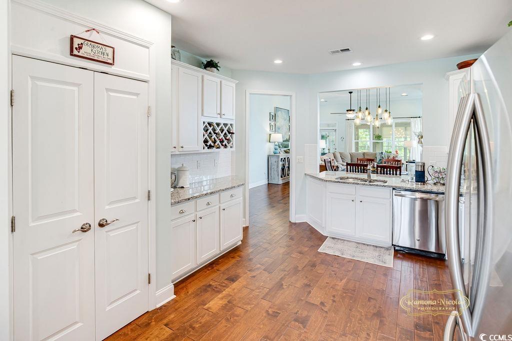 2110 Silver Spring Lane Myrtle Beach, SC 29577 - Photo 6 of 40 Kitchen with appliances with stainless steel finishes, backsplash, dark wood finished floors, white cabinets, and light stone counters