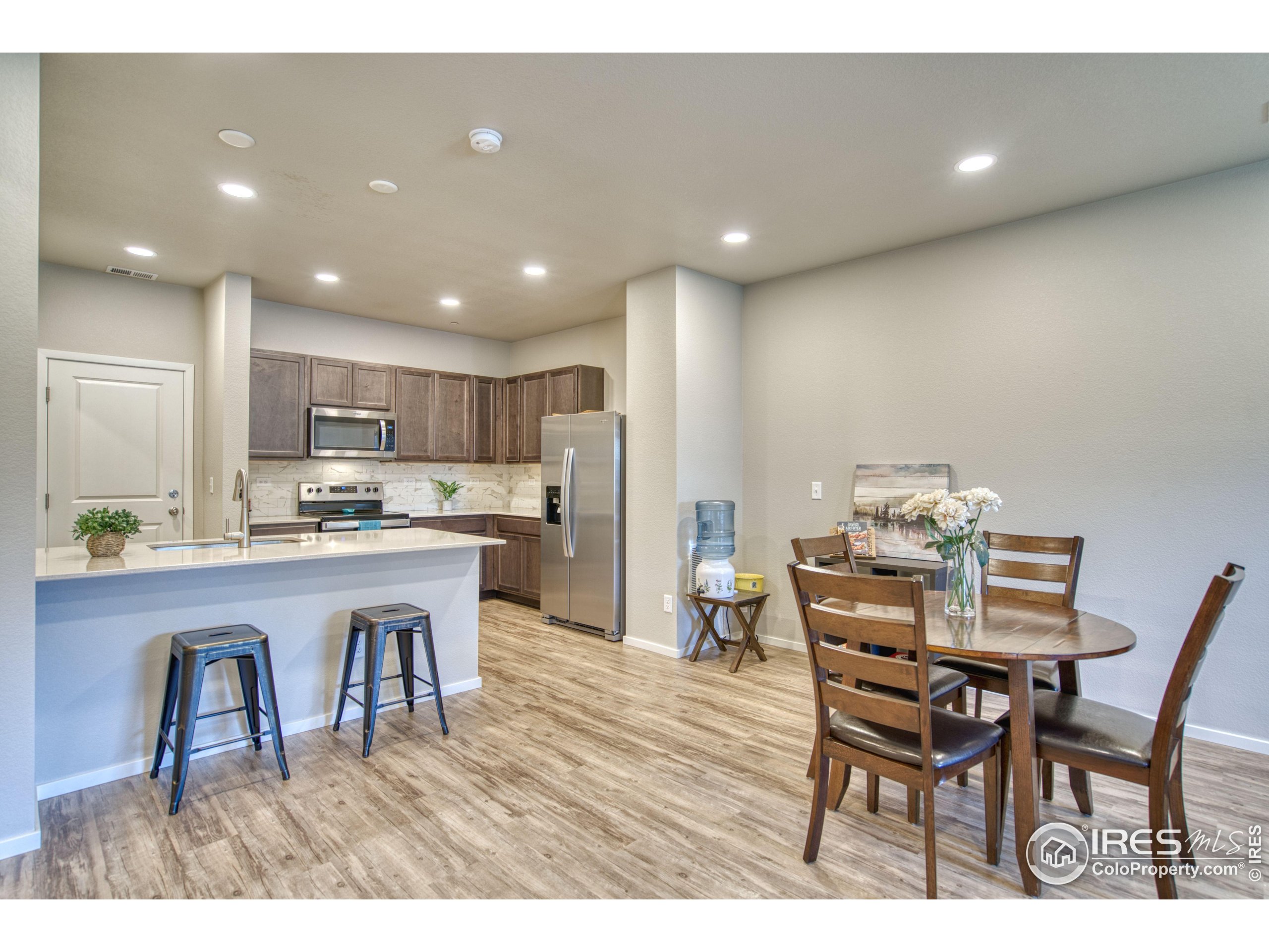 6615 4th St Road, Unit 2 Greeley, CO 80634 - Photo 3 of 31 a kitchen with a dining table chairs and refrigerator