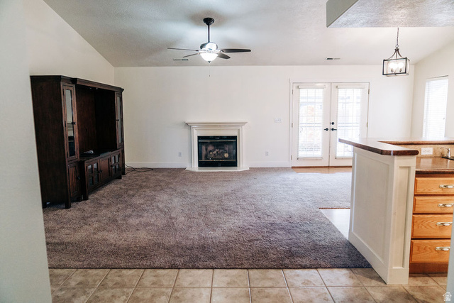 1825 West Mathis Park Place, Unit 40 St. George, UT 84770 - Photo 8 of 28 Unfurnished living room featuring vaulted ceiling, light carpet, ceiling fan, french doors, and a glass covered fireplace