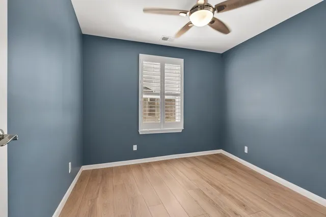 an empty room with a window and a ceiling fan
