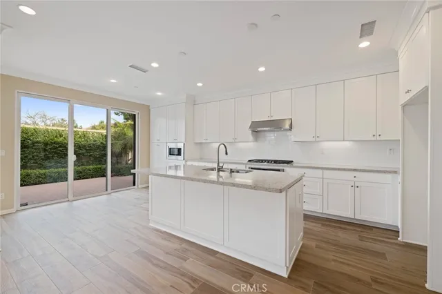a kitchen with stainless steel appliances granite countertop a stove a sink and a refrigerator with wooden floors