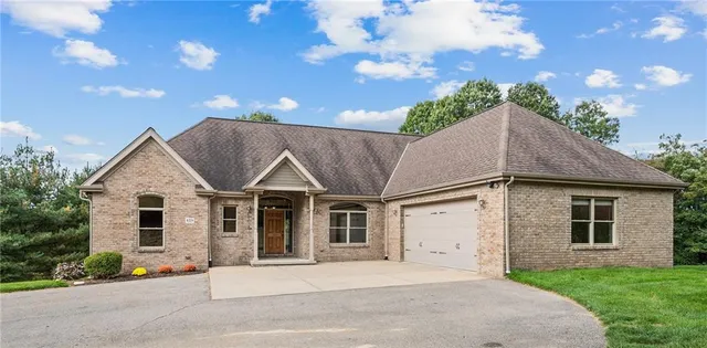 a front view of a house with a garden and trees