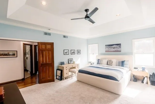 a spacious bedroom with a bed a ceiling fan and a dresser