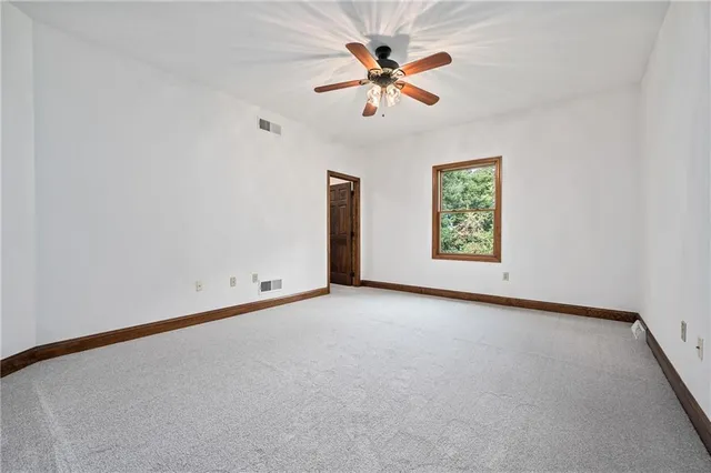 an empty room with window and ceiling fan