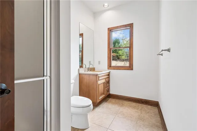 a bathroom with a granite countertop toilet a sink and a mirror