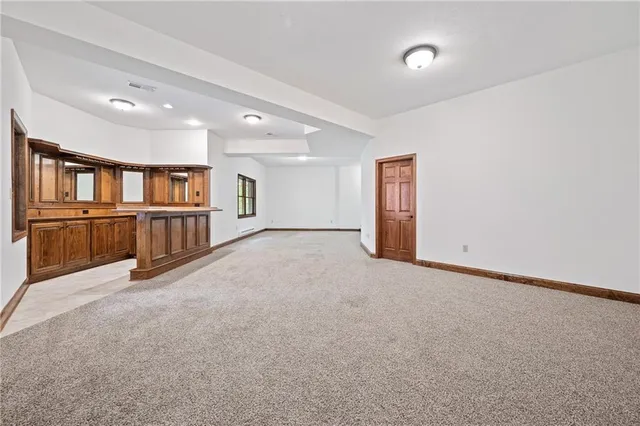 a view of an empty room with wooden cabinet and windows