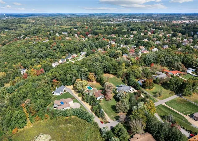 an aerial view of residential houses with outdoor space and trees