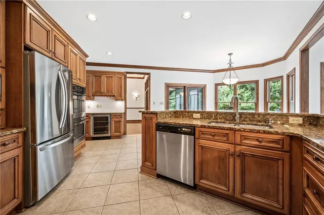 a kitchen with stainless steel appliances granite countertop a refrigerator a stove and a sink