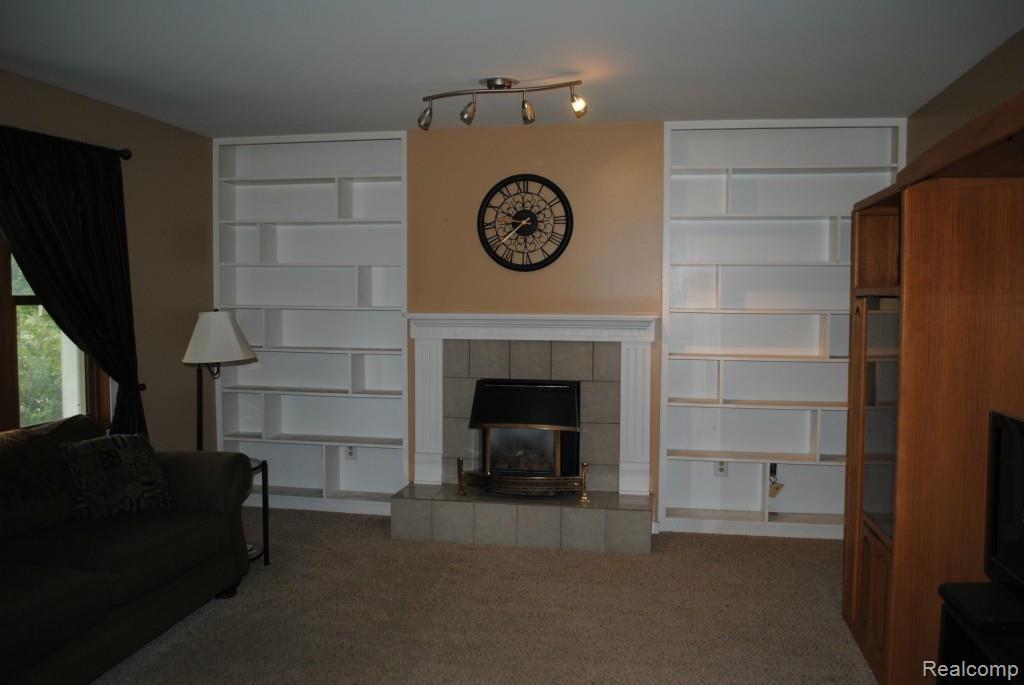 8707 West Van Buren Road Fowlerville, MI 48836 - Photo 8 of 22 Living room with built-in shelving and fireplace.