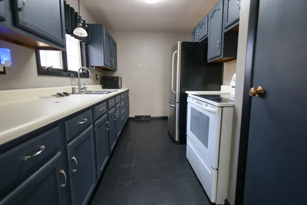 a kitchen with stainless steel appliances granite countertop a refrigerator stove and white cabinets with wooden floor