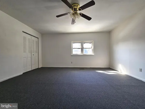 an empty room with windows and fan