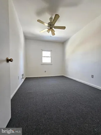 an empty room with a ceiling fan and window