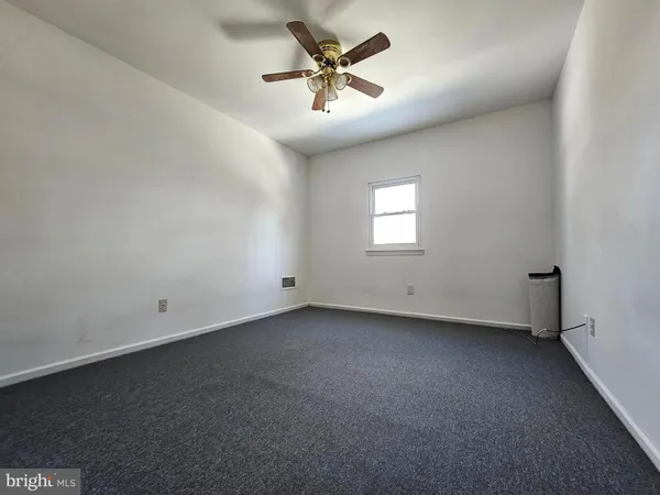 an empty room with windows and ceiling fan