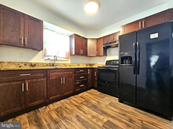 a kitchen with stainless steel appliances granite countertop a refrigerator a sink dishwasher and wooden cabinets with wooden floor