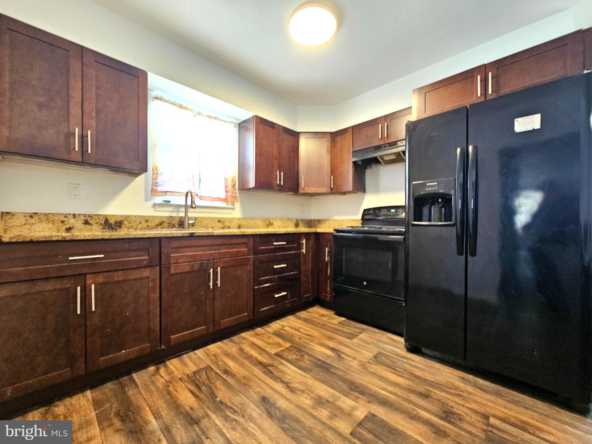 531 Pershing Avenue Darby, PA 19023 - Photo 5 of 33 a kitchen with stainless steel appliances granite countertop a refrigerator a sink dishwasher and wooden cabinets with wooden floor