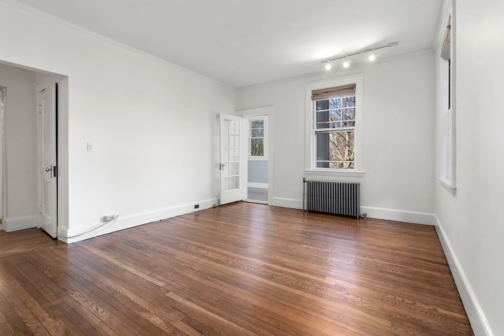 135 Freeman Street, Unit 1A Brookline, MA 02446 - Photo 11 of 22 an empty room with wooden floor and windows