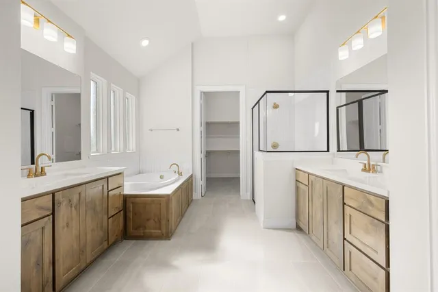 a spacious bathroom with a double vanity sink a mirror and a bathtub