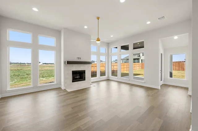 an empty room with wooden floor fireplace and windows