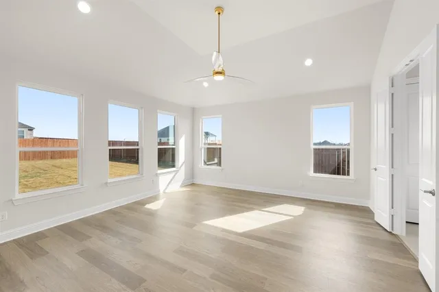 an empty room with wooden floor cabinet and windows