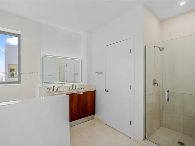 a spacious bathroom with a shower a mirror and a sink