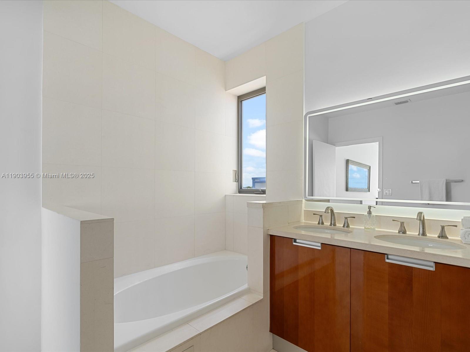 155 North Shore Drive, Unit 1553 Miami Beach, FL 33141 - Photo 39 of 48 a bathroom with a tub sink and mirror