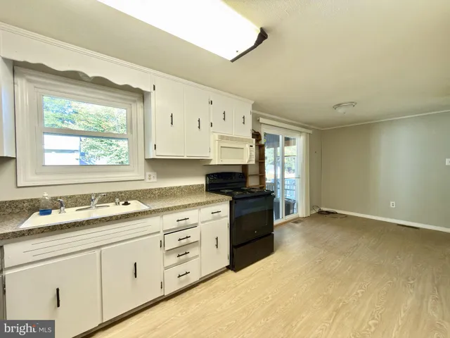a kitchen with granite countertop a stove a sink and a microwave