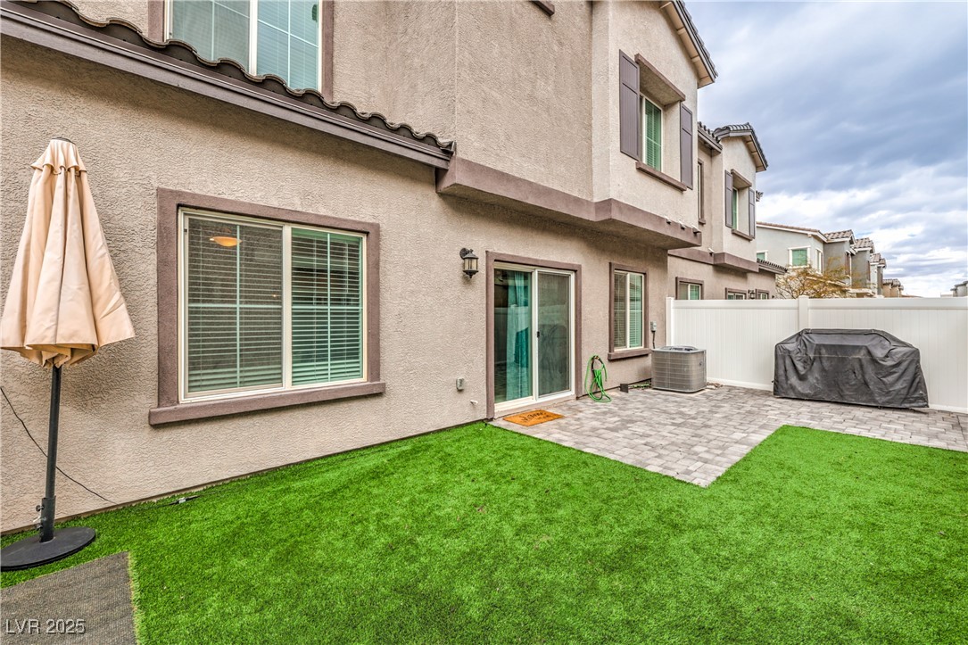 7232 North Decatur Boulevard, Unit 4 North Las Vegas, NV 89084 - Photo 30 of 36 Back of property featuring a patio, cooling unit, fence, a lawn, and stucco siding