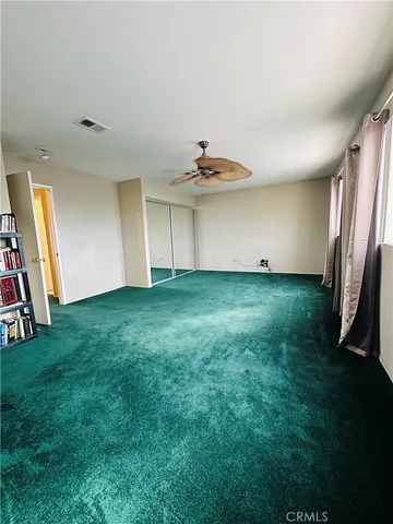 a view of an empty room with window and a kitchen