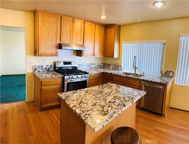 a kitchen with granite countertop a sink a counter top space and stainless steel appliances