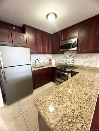 a kitchen with stainless steel appliances granite countertop wooden cabinets a sink and a refrigerator