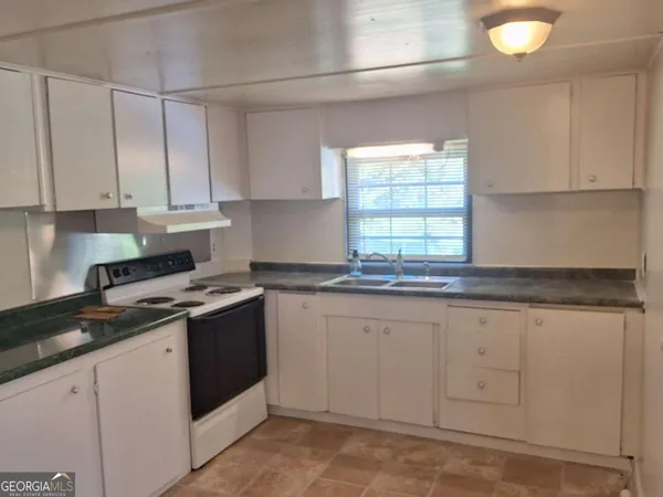 a kitchen with granite countertop white cabinets and white appliances