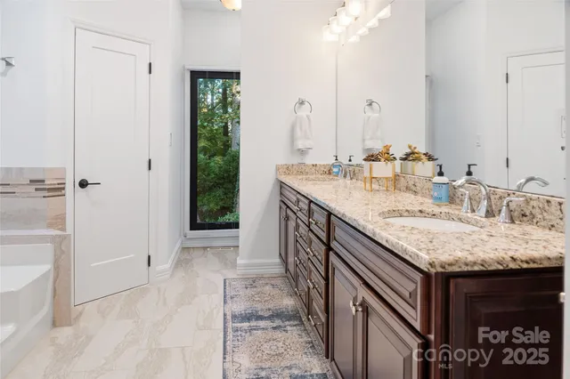 a bathroom with a granite countertop sink a mirror and shower