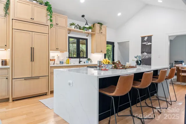 a kitchen with stainless steel appliances granite countertop a refrigerator a sink dishwasher a stove with white cabinets and wooden floor