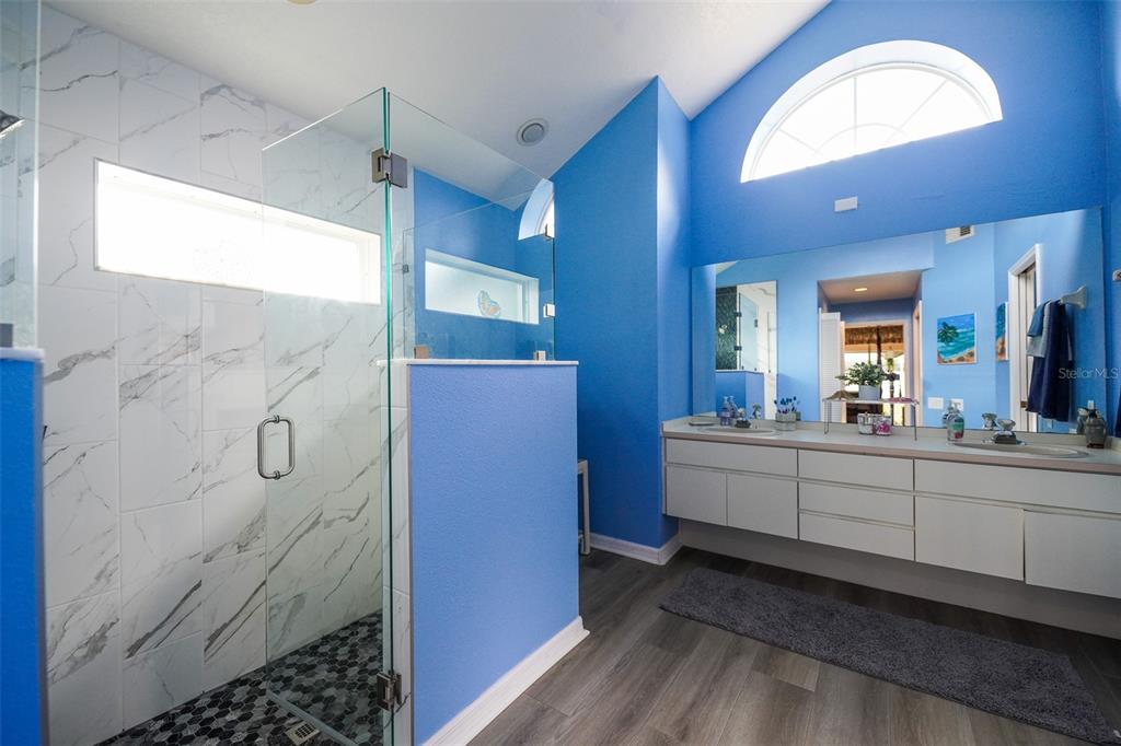 7340 Flyway Drive Spring Hill, FL 34607 - Photo 17 of 32 a bathroom with a mirror a double vanity sink and vanity