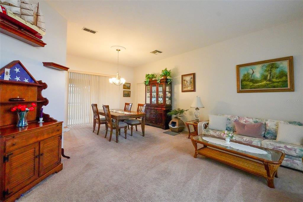 7340 Flyway Drive Spring Hill, FL 34607 - Photo 4 of 32 a living room with furniture and a dining table with potted plants