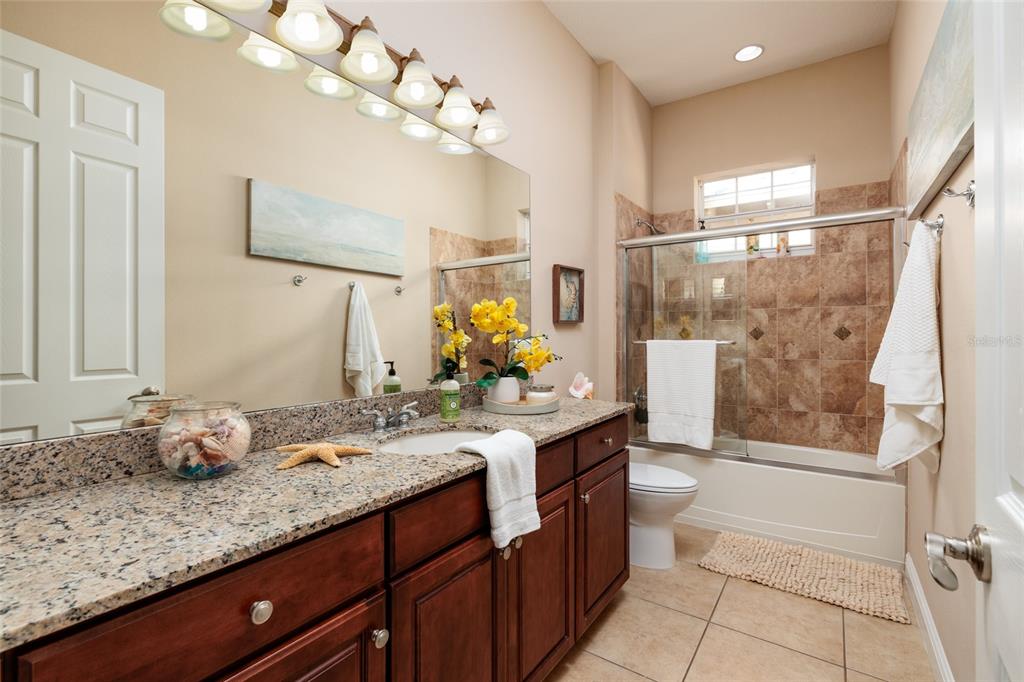 102 Wimbledon Court Redington Shores, FL 33708 - Photo 21 of 66 a bathroom with a granite countertop sink a large mirror and a shower