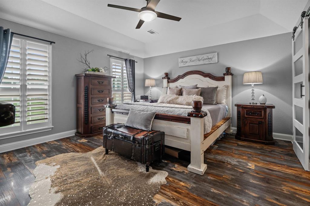 175 Porter Road Bartonville, TX 76226 - Photo 18 of 40 This lovely, serene primary bedroom features vaulted ceilings, a ceiling fan, warm tones, and windows framing scenic views for a peaceful retreat-like atmosphere.