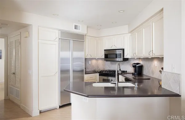 a kitchen with stainless steel appliances granite countertop a sink and a refrigerator
