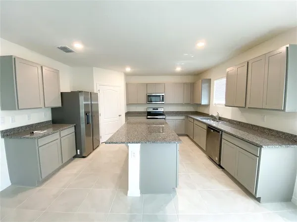 a large kitchen with stainless steel appliances kitchen island granite countertop a stove a sink dishwasher and a refrigerator