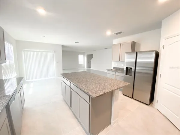 a kitchen with stainless steel appliances granite countertop a refrigerator a sink a stove and a refrigerator with wooden floor