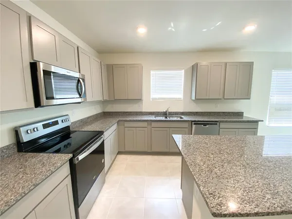 a kitchen with stainless steel appliances granite countertop a sink stove and microwave