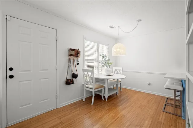 a dining room with wooden floor a chandelier a wooden table and chairs