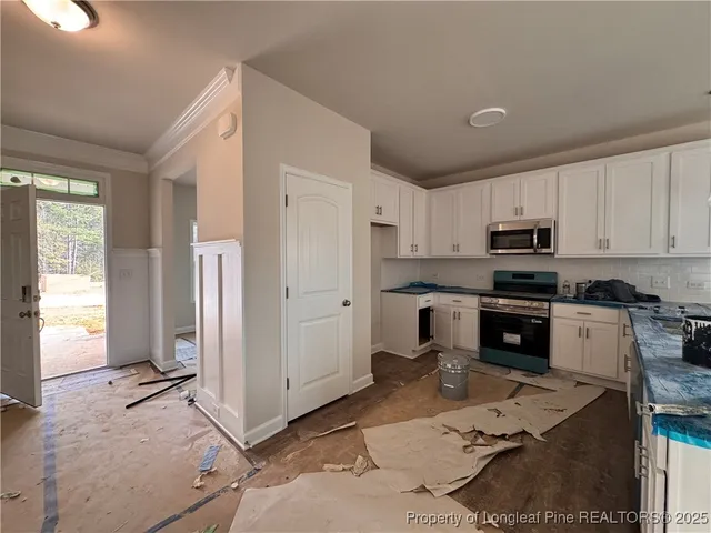 a kitchen with granite countertop a refrigerator and a stove top oven