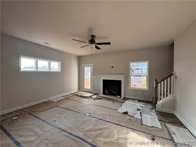 a view of livingroom with fireplace ceiling fan and windows