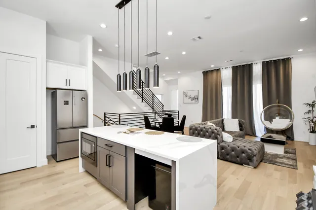 a large kitchen with stainless steel appliances kitchen island a stove a refrigerator a oven with white cabinets and wooden floor