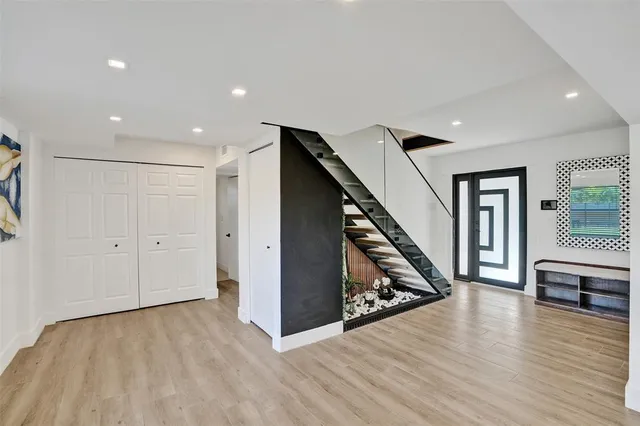 a view of an empty room with wooden floor and stairs