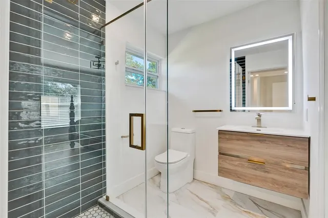a bathroom with a granite countertop sink a toilet and mirror