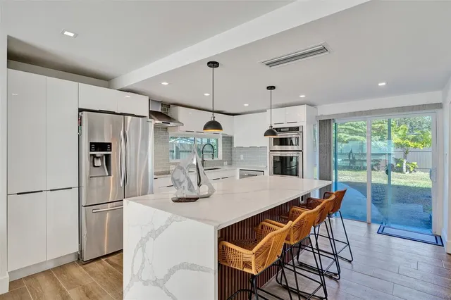 a kitchen with stainless steel appliances a dining table chairs refrigerator and stove