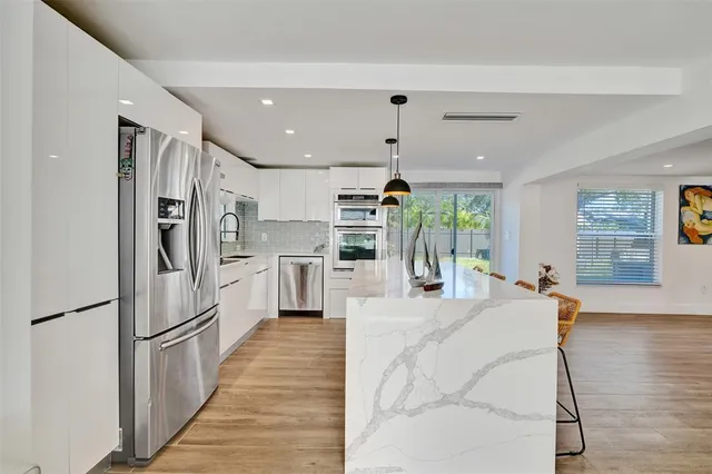 a kitchen with stainless steel appliances kitchen island granite countertop a refrigerator and a stove top oven