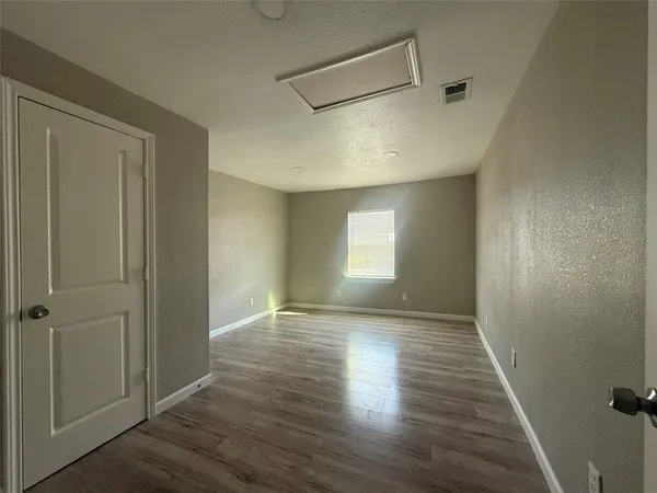 a view of an empty room with window and wooden floor